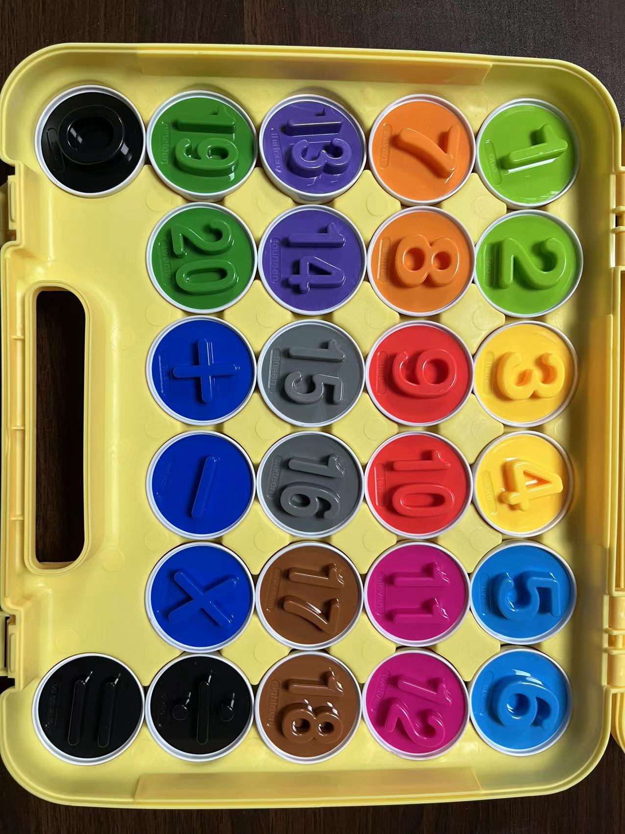 Set of colorful number stamps in a yellow case on a dark surface