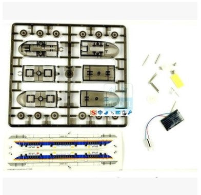 Model kit components including a plastic model of a vehicle, tools, and electronic parts on a white background.